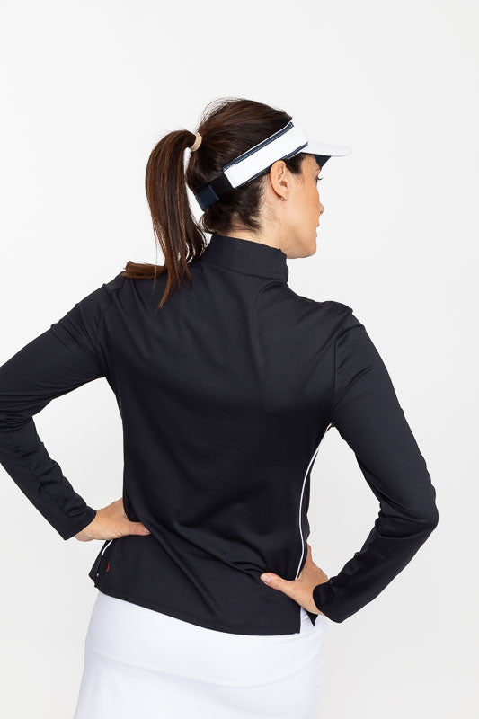 Back view of a woman with her hands on both hips wearing a white No Hat Hair Visor and a Keep It Covered Long Sleeve Golf Top in black