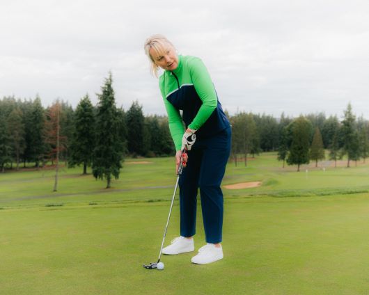 A woman swinging a golf club on the course 