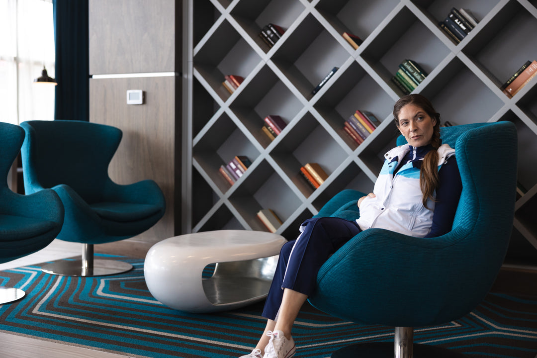 women sitting in front of bookcase wearing white golf vest and navy pants