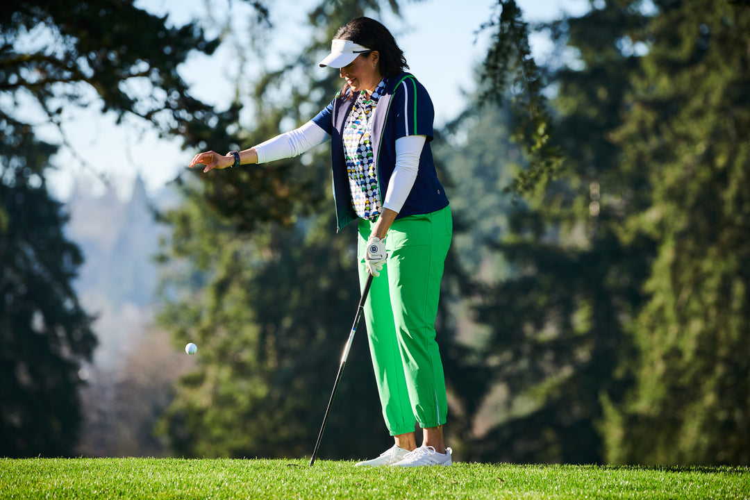 A woman dropping a golf ball on a golf course