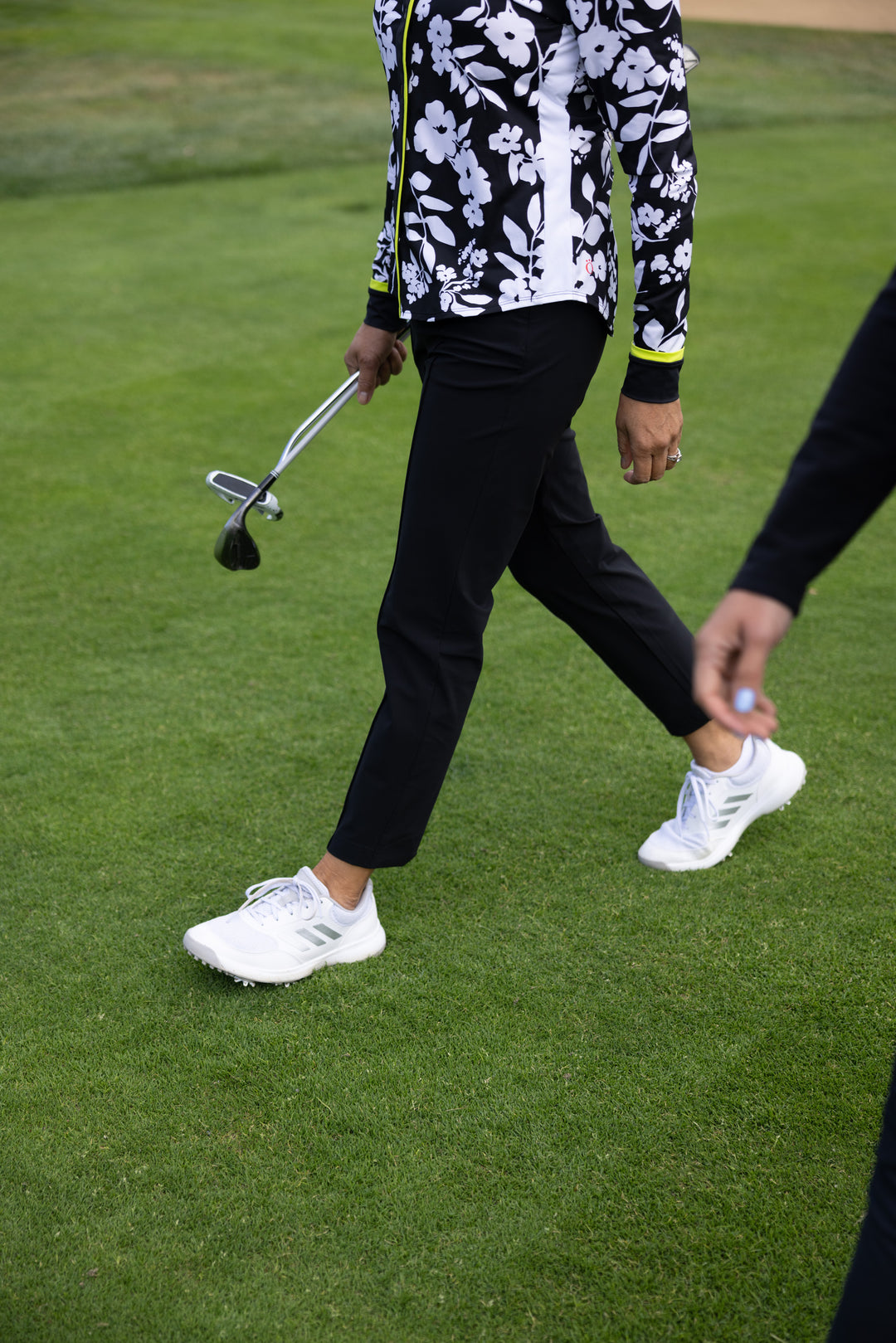 Woman wearing black golf pants walking on golf course 