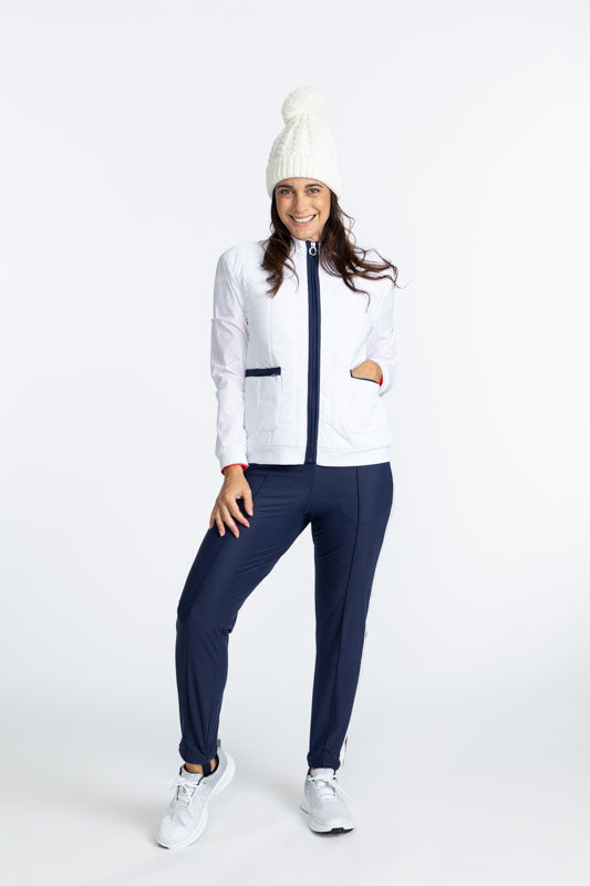 A woman wearing a quilted jacket with a beanie and navy blue stirrup pant. 