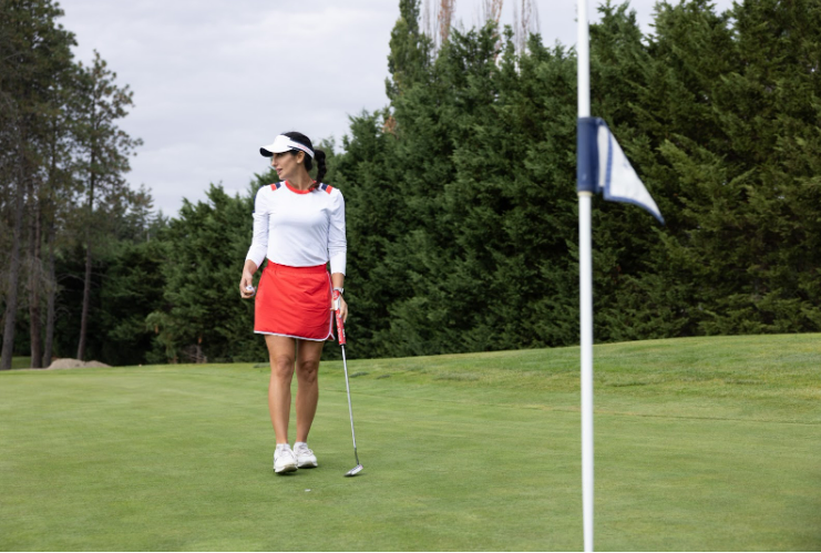 Women standing next to golf hole wearing sun protective clothing