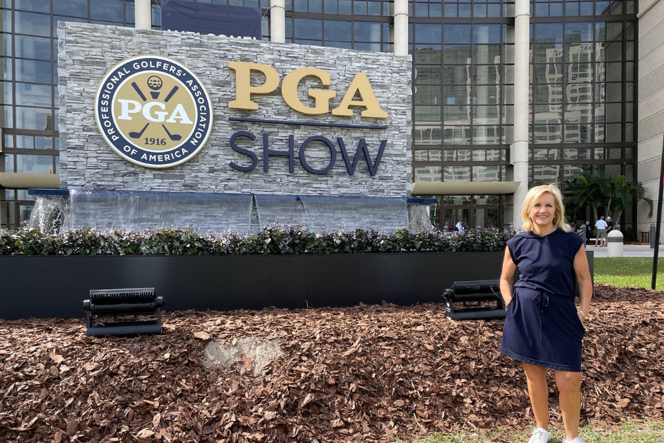 KINONA's co-founder Dianne Celuch standing in front of PGA show sign.