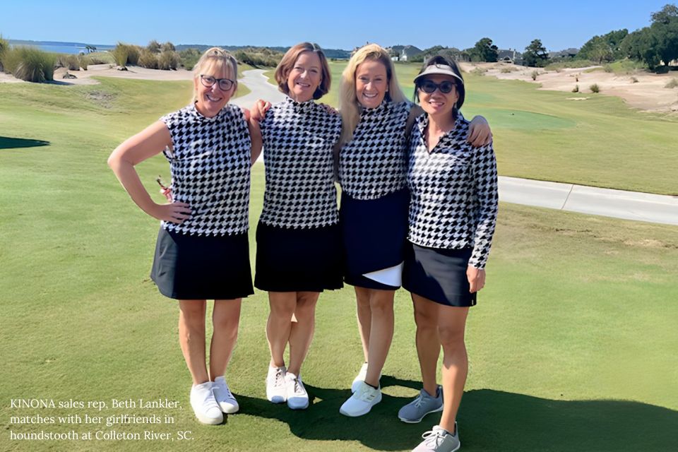 A smiling female foursome standing together on putting green in black and white checkered KINONA attire.