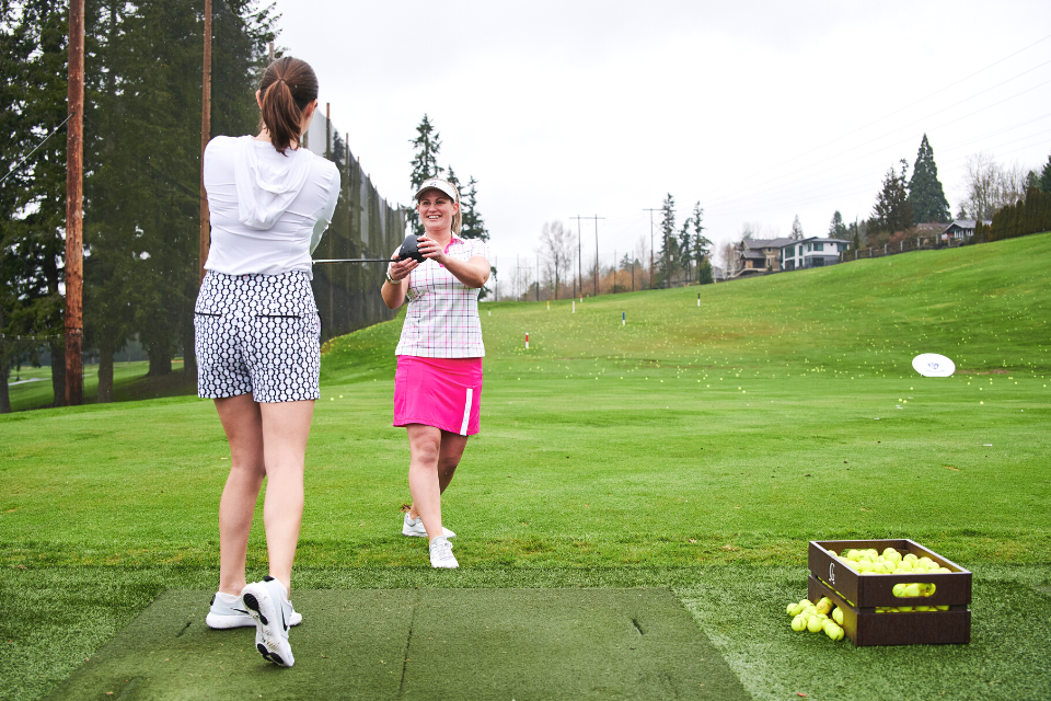 A golf trainer and student learning golfing tips for increased stamina on the green grass.