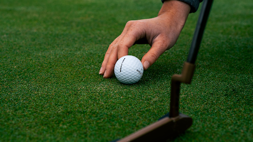 A hand placing a ball on the golf course 