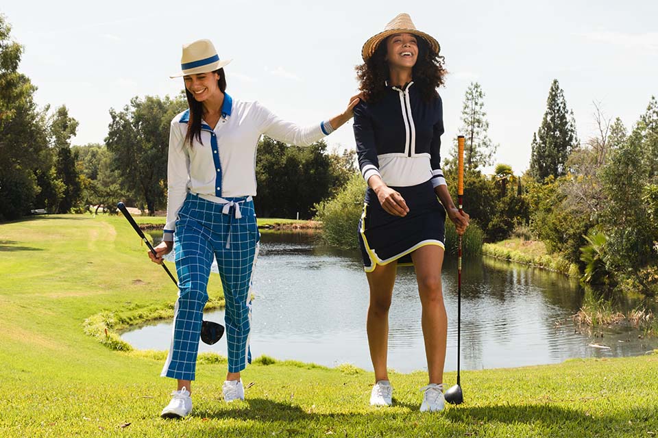Two female golfers on green grass course in KINONA fashion from Nordstrom and Dillard's.