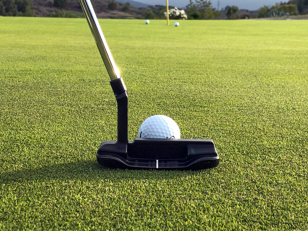 A golf club about to hit a golf ball