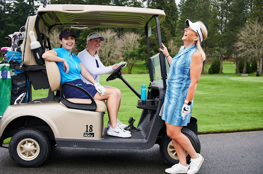 Three women chatting near a golf cart