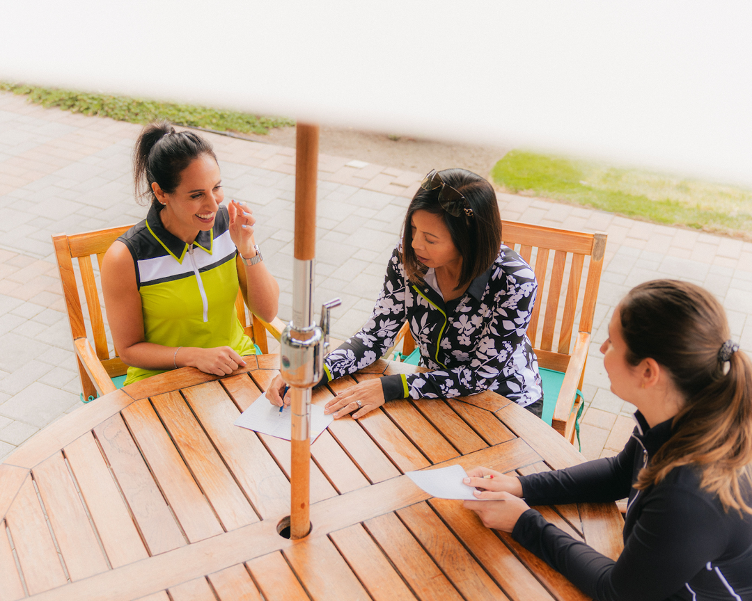 Three women sitting at table looking over score cards