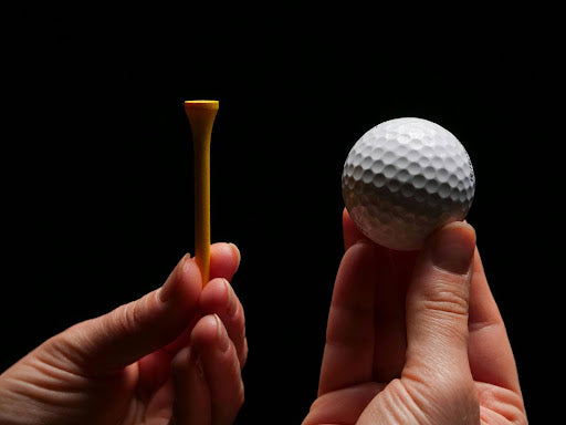 Hands holding a golf ball and a ball tee