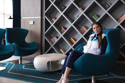 Woman in puffer vest sitting in lobby chair