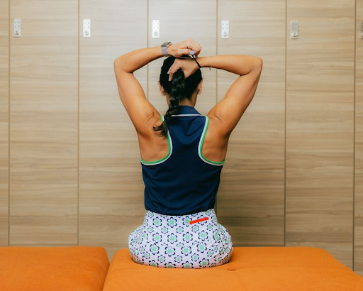 A woman putting her hair up in a ponytail 