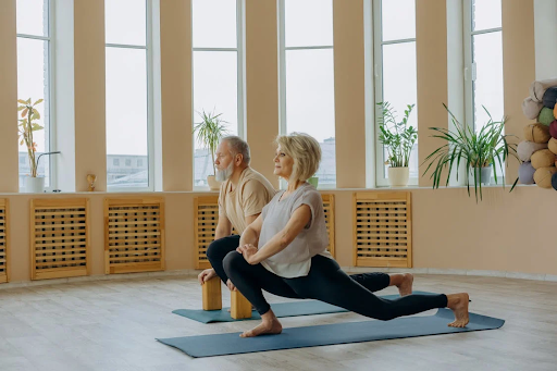 Two older people stretching on a yoga mat