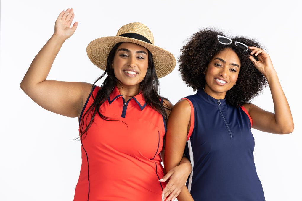Two women linking arms in KINONA’s signature deep orange and navy blue tops. 
