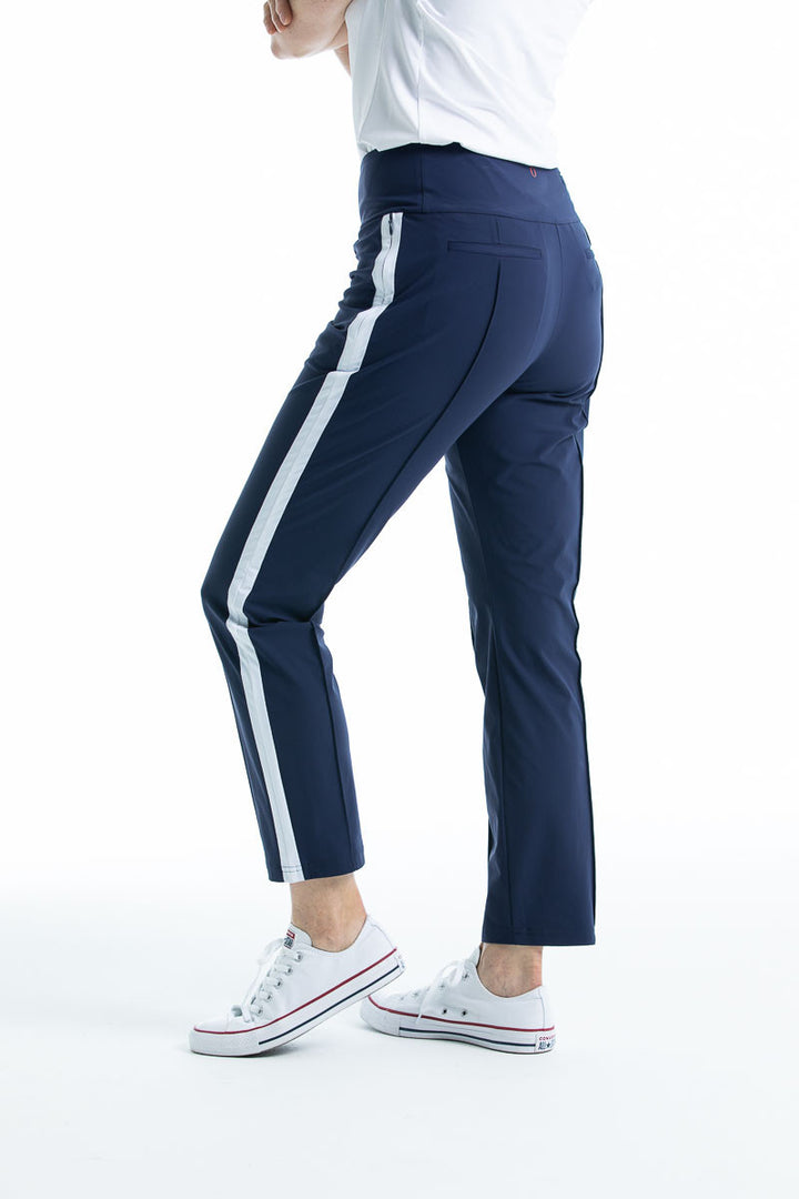 Woman wearing navy blue Tailored Track golf pant with white trim down the side of leg.