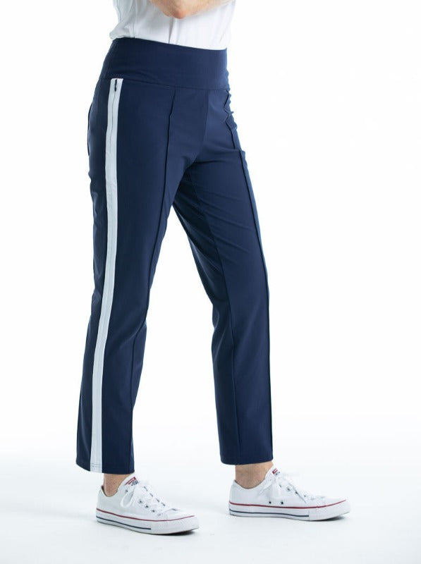 Side view of woman in navy blue Tailored Trim golf pants with white trim down the side of the leg.