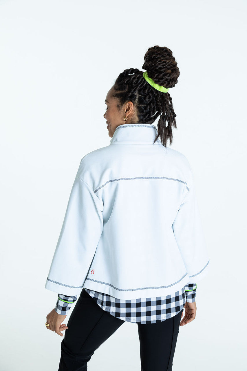 Back view of a woman wearing a white To the Nines golf jacket