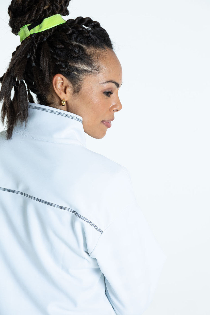 Close back view of a woman wearing a white To the Nines golf jacket
