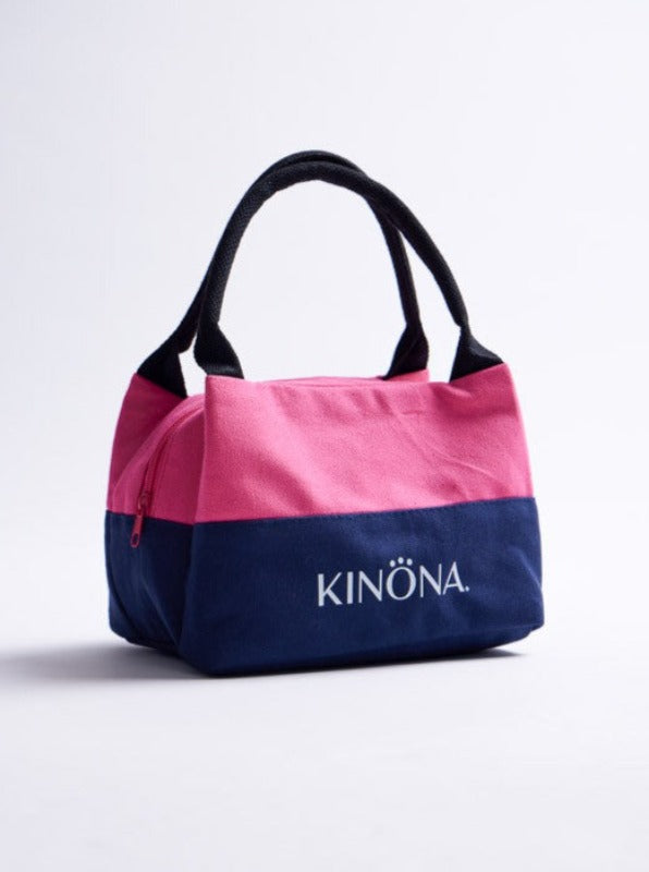 The Super Snack Sack in open air pink. This sack has black handles, the top half of the bag is in open air pink and the lower half is in navy blue with the KINONA logo embroidered in white on the navy blue background.