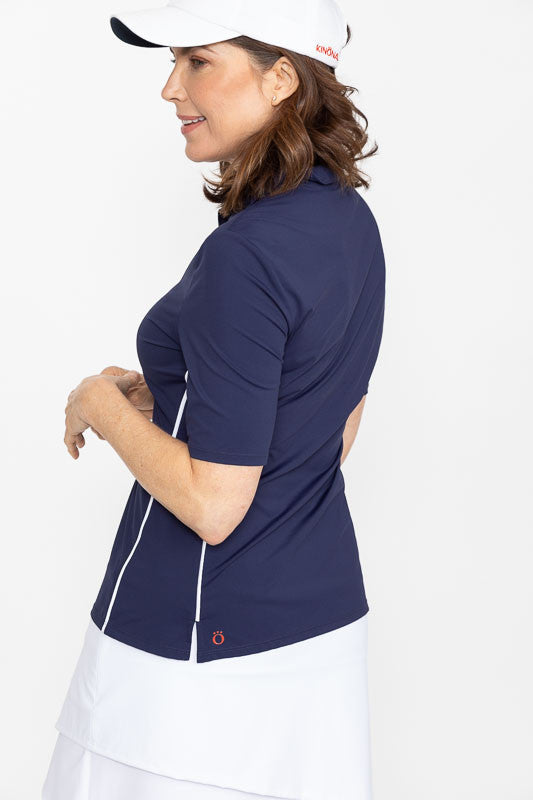 Side view of a woman wearing a white We've Got You Covered Hat and a Keep It Covered Short Sleeve Golf Top in navy blue