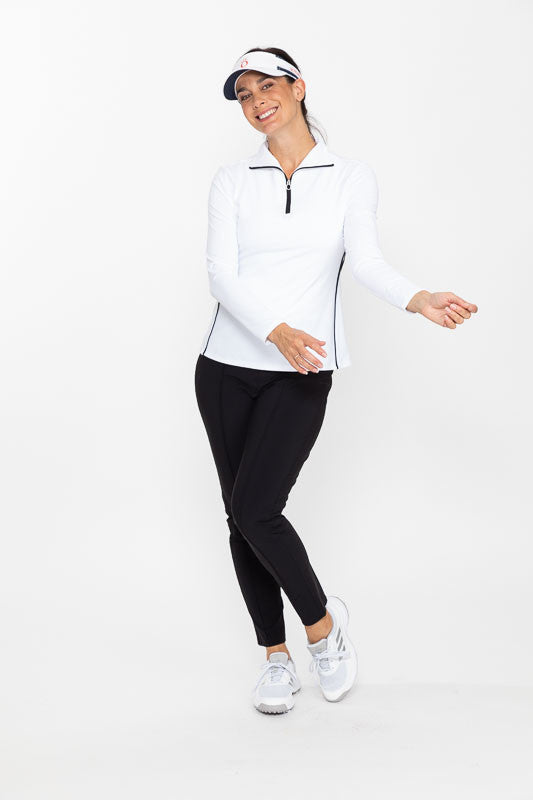 Smiling woman wearing a white No Hat Hair visor, a Keep It Covered Long Sleeve Golf Top in white, and a pair of Smooth Your Waist Crop Golf Pants in black