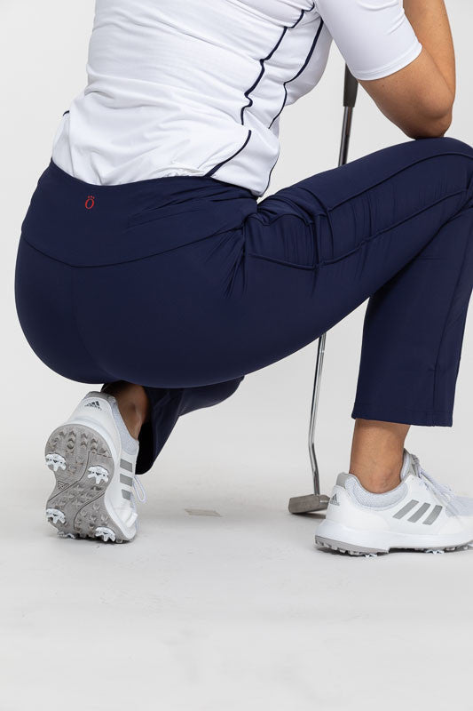 Back view of a woman crouching down in a pair of Smooth Your Waist Crop Pants in navy blue