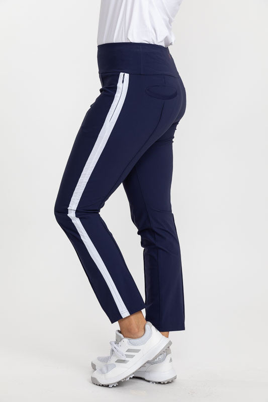 Left side view of a woman wearing a pair of Tailored Track Golf Pants in navy blue with a white stripe down the side of the leg