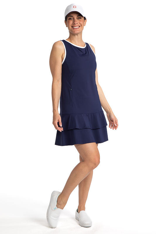 Full front view of a smiling woman wearing the On In Two Sleeveless Golf Dress in Navy Blue and a We've Got You Covered baseball cap in white