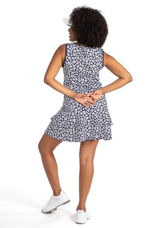 Back view of a woman golfer wearing the On In Two sleeveless golf dress in Vinca Print