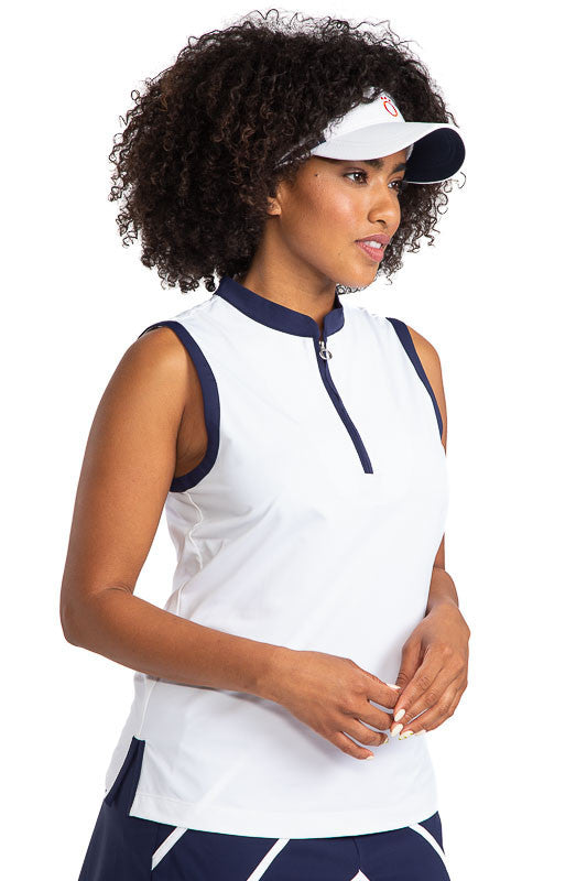 Front and right side view of a woman wearing the Zip It and Rip It Sleeveless Golf top in white and a No Hat Hair Visor in white. This top has navy blue accents at the neckline and around each sleeve.