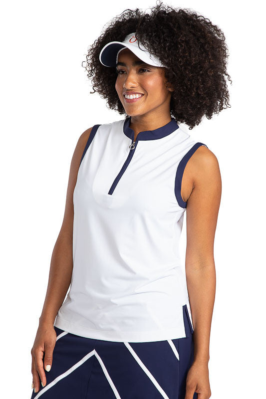 Full view of a smiling woman wearing the Zip It and Rip It Sleeveless Golf top in white and a No Hat Hair Visor in white. This top has navy blue accents at the neckline and around each sleeve.