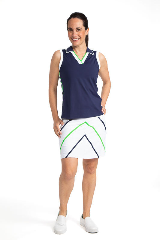 Full front view of a smiling woman wearing the Show Me The Way Golf Skort in White and the On Par Sleeveless Golf Top in Navy Blue. This skort has accents in the form of two diagonal line on both sides of the front of the skort in Fairway Green and Navy B