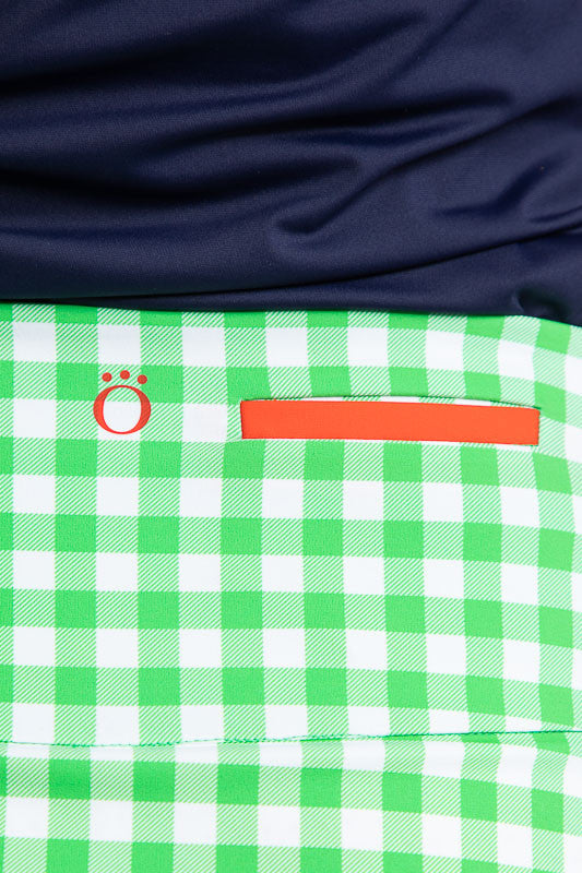 Close back view of the waist of the the Ready Play Golf Skort in Go Go Gingham. The Go Go Gingham print consists of green and white checks. This golf skort also has navy blue accents down the length of the zipper on both sides, a white front zipper, navy 