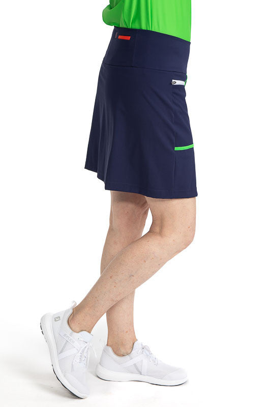 Right side view of the Ready Play Golf Skort in Navy Blue. This golf skort also has Fairway Green accents down the length of the zipper on both sides, a white front zipper, Fairway Green curved L-shape accents around each pocket, and white horizontal zipp