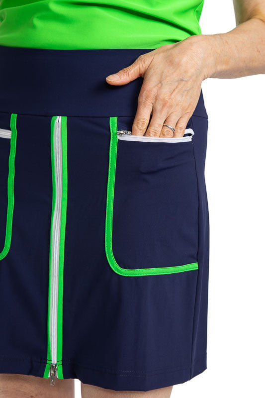 Close front and left side view of the Ready Play Golf Skort in Navy Blue. This golf skort also has Fairway Green accents down the length of the zipper on both sides, a white front zipper, Fairway Green curved L-shape accents around each pocket, and white 