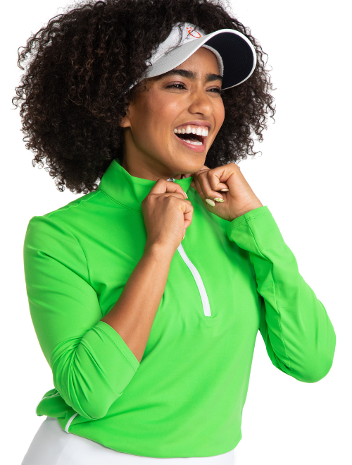 Smiling woman golfer wearing the Keep It Covered Long Sleeve Golf Top in Fairway Green and the No Hat Hair Visor in White. 