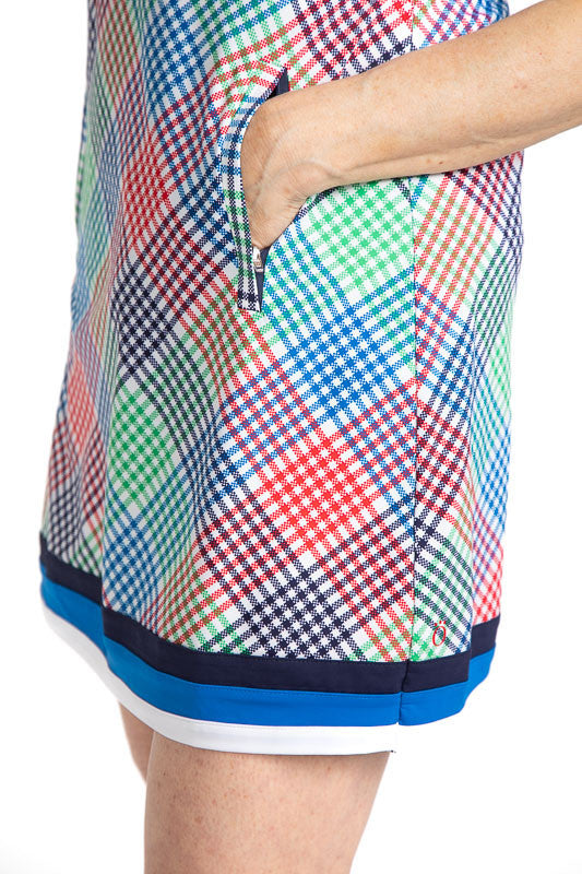 Close left side view of the Zip it and Rip it Sleeveless Golf Dress in Vacation Plaid. This plaid consists of red, blue, white, and green. There are three stripes around the bottom hemline of this dress in navy blue, azure blue, and white.