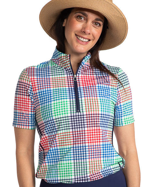 Smiling woman wearing the Keep It Covered Short Sleeve Golf Top in Vacation Plaid. Vacation Plaid consists of a small, checkered pattern of red, blue, green and white.