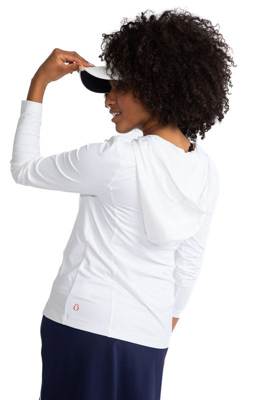 Back and left side view of a woman golfer wearing the Layer It Up Long Sleeve Hoodie Golf Top in White and the No Hat Hair Visor in White