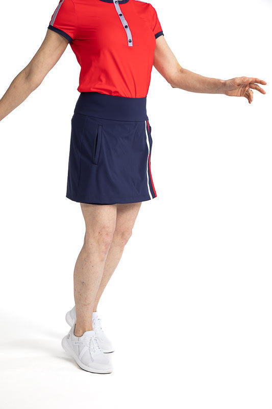 Front view of the Skort and Short Golf Skort in Navy Blue and the Approach Shot Short Sleeve Golf Top in Cherry Red. This skort has two vertical stripes down the front left side in white and cherry red. 