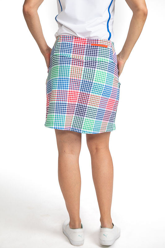 Complete back view of the Pocket Envy Golf Skort in Vacation Plaid. Vacation Plaid consists of a small, checkered pattern of red, blue, green and white. There is one stripe of navy blue down either side of the skort from the bottom of the pocket to the he