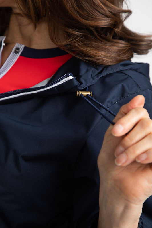 Tight front left side view of the hood drawstring on the Pack and Play Lightweight Golf Jacket in Navy Blue. This jacket folds into a pouch that easily fits in your golf bag.