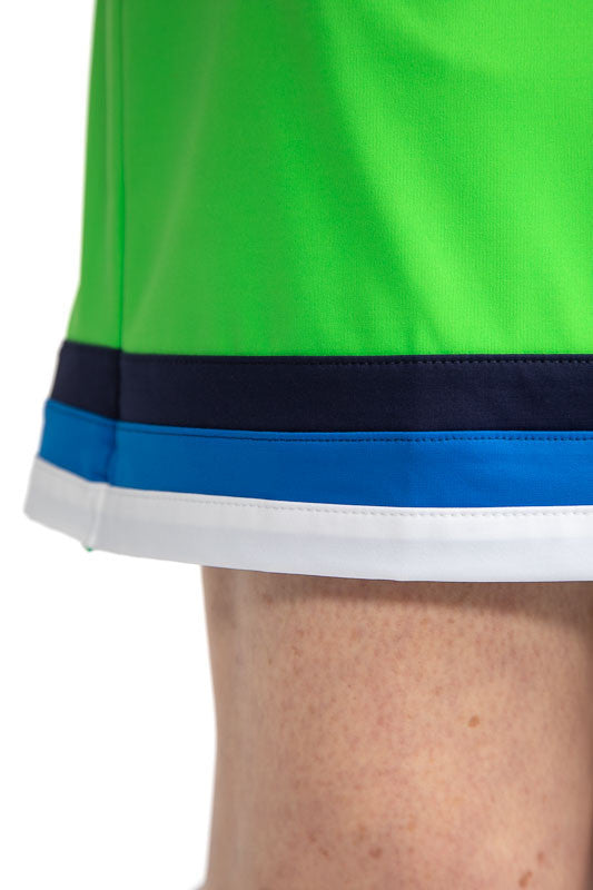 Close front and right side view of the hemline on the On the Fringe Golf Skort in Fairway Green. In this view, you get a close look at the three stripes around the bottom of this skort in Navy Blue, Azure Blue, and White. 