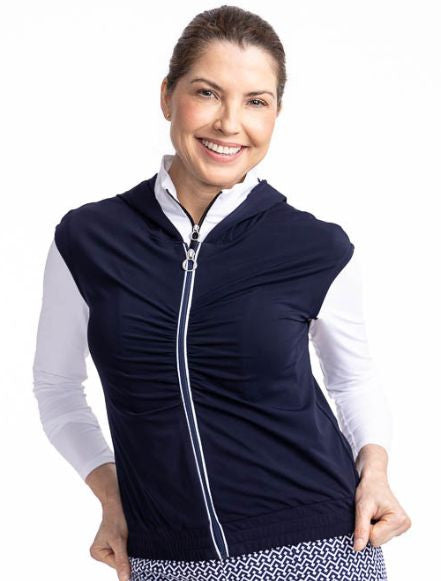 Close front view of a smiling woman wearing the Fall Ball Golf Vest in Navy Blue. This is a solid navy blue vest with a white front zipper and elastic waistband.