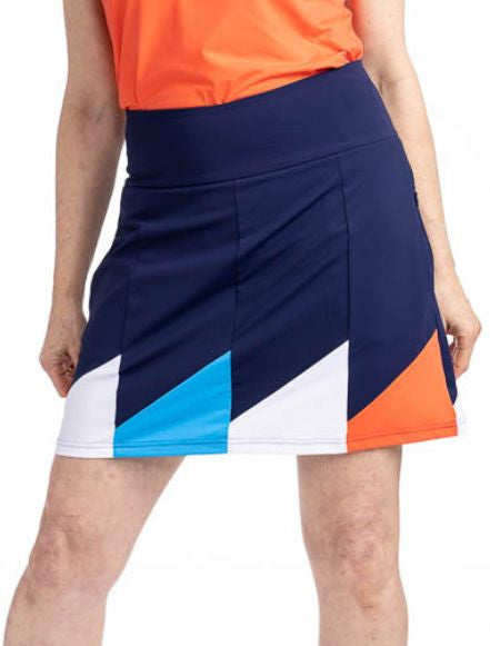 Close front view of the Helping Wind Golf Skort in Navy Blue. This is a navy blue skort with alternating triangles shaped like golf flags of white, pacific blue and coral red around the hemline. It features two in-seam pockets and a built-in medium grey s