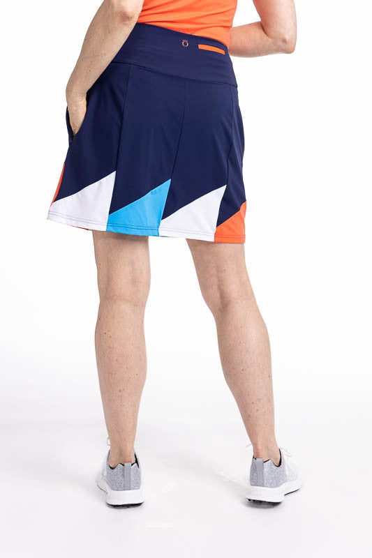 Back view of the Helping Wind Golf Skort in Navy Blue. This is a navy blue skort with alternating triangles shaped like golf flags of white, pacific blue and coral red around the hemline. It features two in-seam pockets and a built-in medium grey shortie 