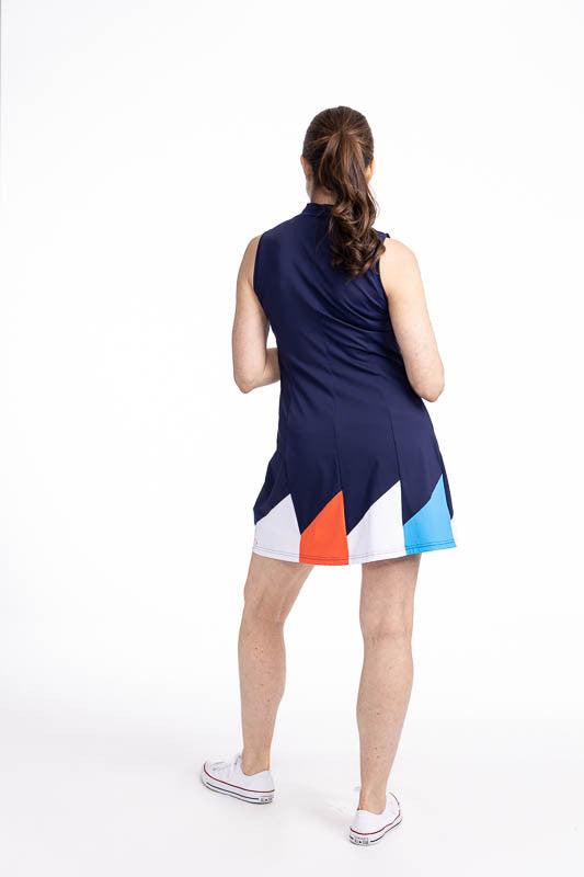 Full back view of the Helping Wind Sleeveless Golf Dress in Navy Blue. This is a solid navy blue dress with alternating triangles shaped like golf flags in white, pacific blue, and coral red around the hemline. It also features two side pockets and a buil
