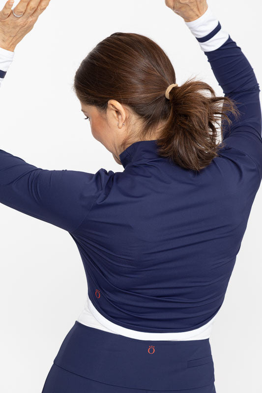 Back view of a woman with both arms up in the air wearing a Sun's Out Zip Front Shrug in Navy Blue